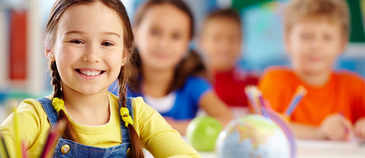 Preschool children smiling in a classroom.